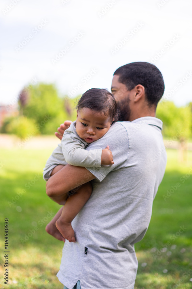 Father holding his baby in a park, enjoying a sunny day Father holding his baby in a park, enjoying a sunny day