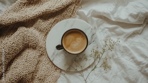 Warm cup of coffee on cozy blanket with heart-shaped latte art in soft mornin...