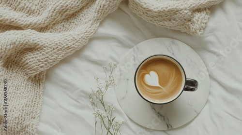 Warm cup of coffee on cozy blanket with heart-shaped latte art in soft mornin...