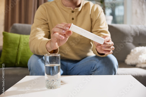 Man holding tube with vitamins, solvable tablet which dissolves in water. Male model demonstrate plastic tube with negative space. Concept of illness, health insurance, pharmaceutical, medicine. Ad.