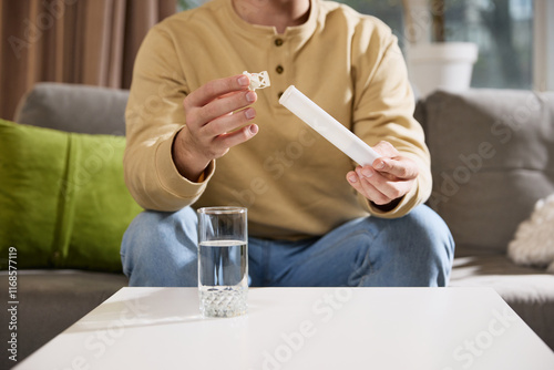 Fotografia Cropped photo of ale hands unpack tube with medicine, soluble tablets with vitamins at desk at home