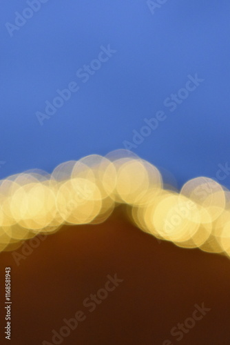 Golden yellow bokeh balls shining bright in the evening sky.