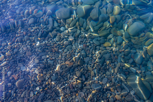 Obraz na płótnie Underwater pebble backgrounds. Colorful stones sea bottom in the sun rays. View from above through clear water. Seascape wallpaper texture. Defocus. w salonie