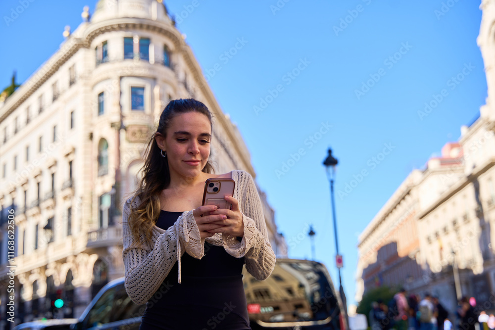 Fototapeta premium Young Caucasian woman using smartphone in front of historic building