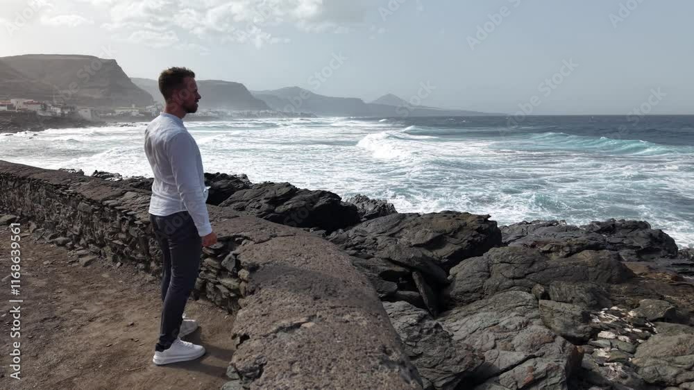 Man gazes at ocean waves on Gran Canaria's coastline Man gazes at ocean waves on Gran Canaria's coastline