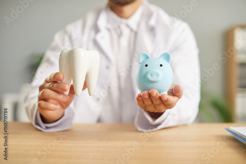 фотографія Portrait of a male dentist doctor sitting at the desk in dentistry clinic and holding piggy bank and healthy white tooth in hands