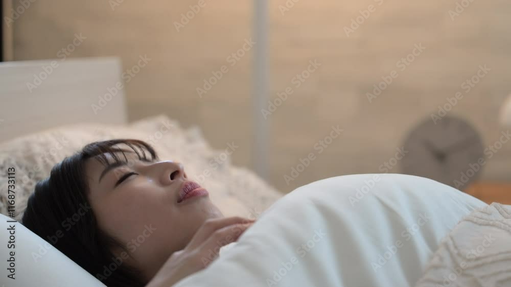 間接照明で眠りにつく女性　ベッドの睡眠や安眠のイメージのクローズアップの動画　ニュートラルな色