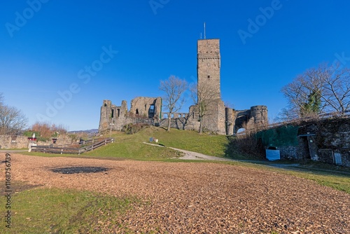 A castle tower and ruins on a hill under a bright blue sky photo