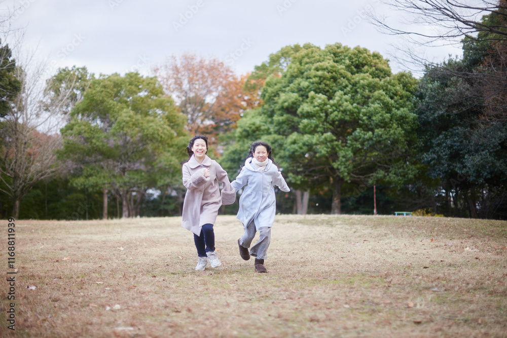 Fototapeta premium 冬の朝の公園で元気で楽しく遊んでいる子供姉妹の姿