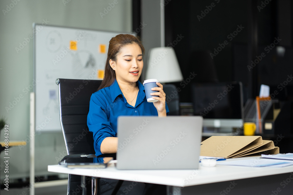 Asian businesswoman sits in a office working and enjoys a coffee. Asian businesswoman sits in a office working and enjoys a coffee.
