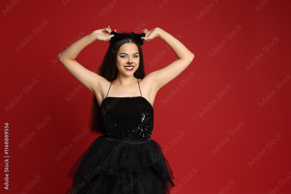 Woman with cat makeup and ears in beautiful dress on red background Woman with cat makeup and ears in beautiful dress on red background
