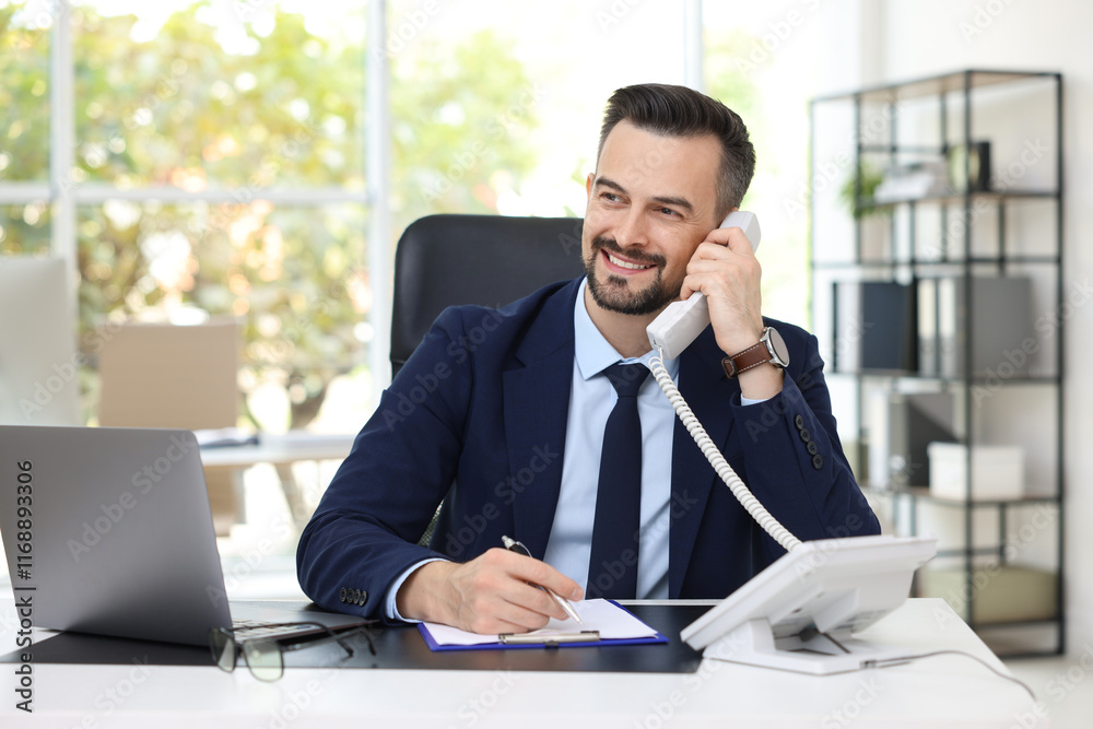 Happy banker talking on phone at table in office