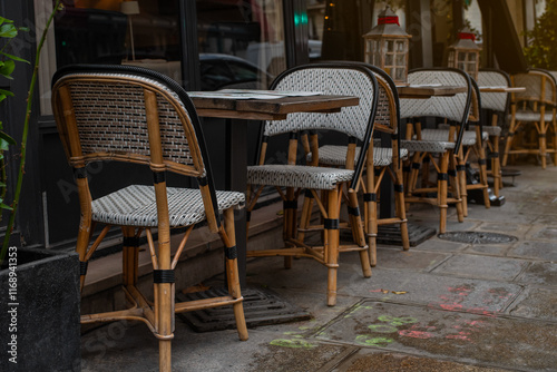 Quintessential Parisian café ambiance on a charming street in the 7th arrondissement. Elegant wicker chairs and wooden tables create an inviting scene perfect for dining, leisure, or urban lifestyle  photo