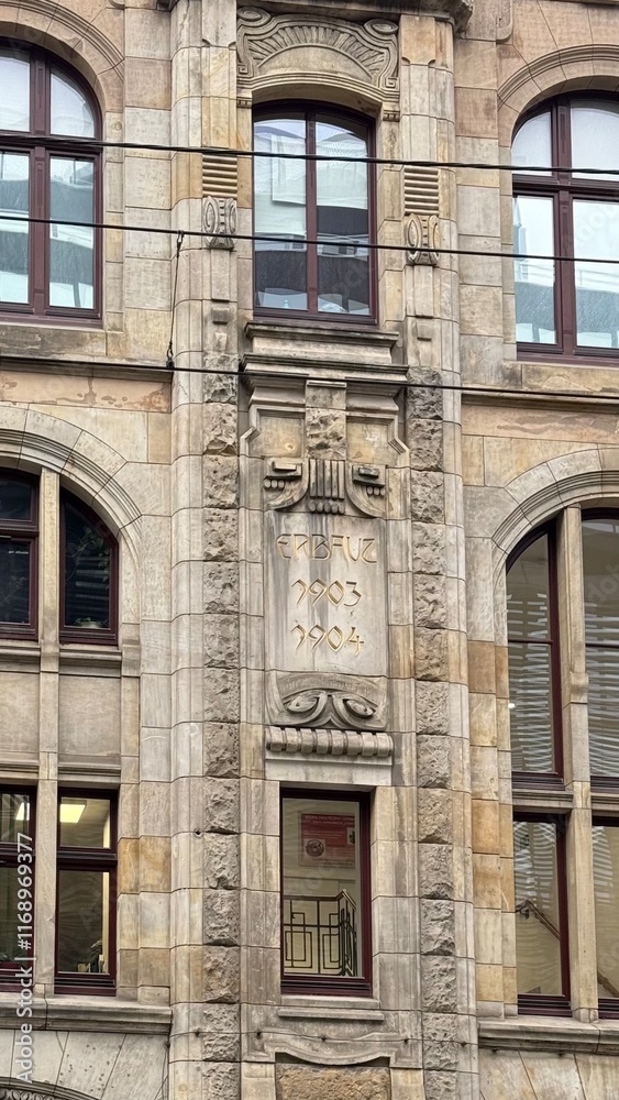 Obraz premium Detailed architecture of an old building with stone finishing and tall windows. Elements of Renaissance style, sculptural decor, and a sense of historical atmosphere.