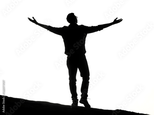 Silhouette of a person with arms outstretched at dusk.