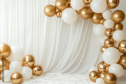 Gold and white balloons adorn a white fabric backdrop