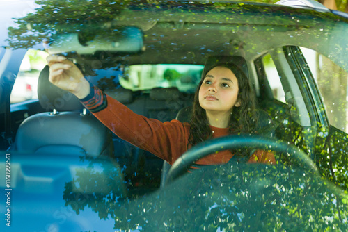 Konstfotografi Teenage driver adjusting the rearview mirror on a sunny day