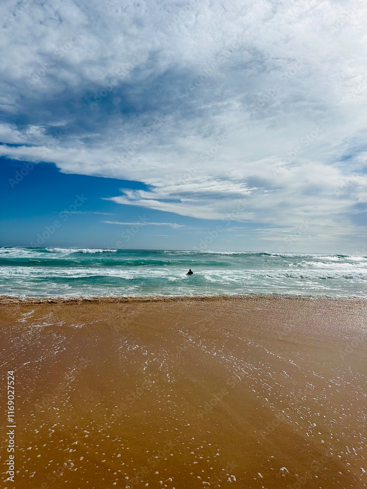 Surfer entering the ocean from a beach in melbourne with his surfboard Surfer entering the ocean from a beach in melbourne with his surfboard
