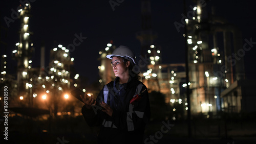 Petroleum oil refinery  female engineer worker in the oil and gas industrial with personal safety equipment PPE to communicate and work with a digital tablet and walkie-talkie photo