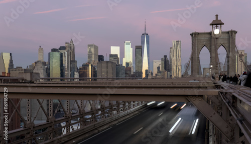 cars driving over the brooklyn bridge from manhattan new york city (long exposure light trails) traffic commute commuters traveling to work jobs (skyline background at dawn sunrise) dark night time