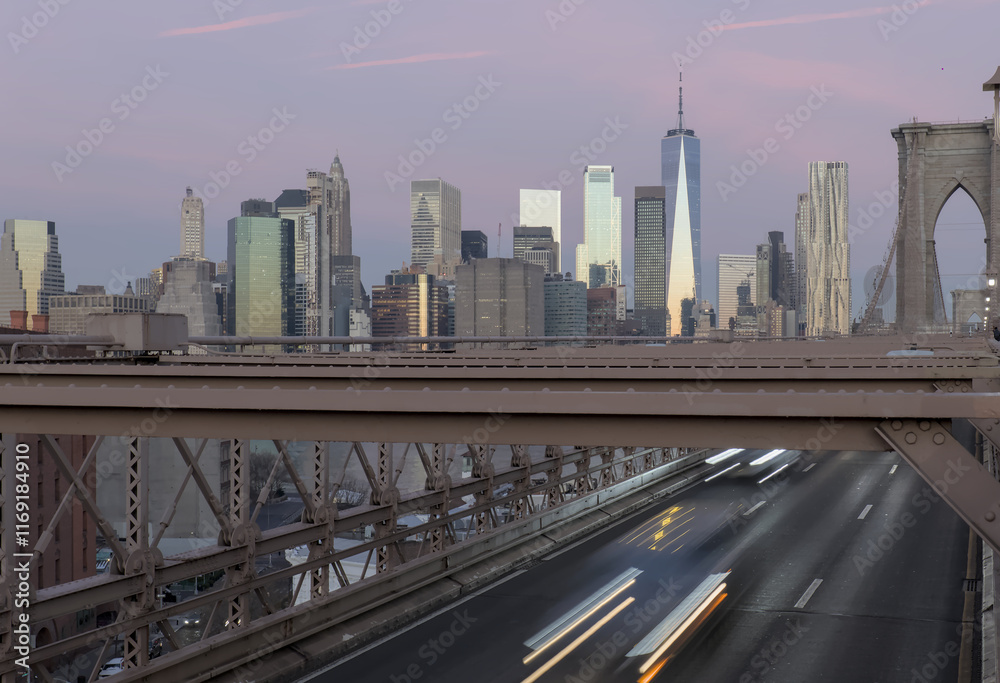 Obraz premium cars driving over the brooklyn bridge from manhattan new york city (long exposure light trails) traffic commute commuters traveling to work jobs (skyline background at dawn sunrise) dark night time