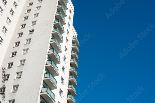 Low angle view of a high rise residential apartment block against a clear blue sky.