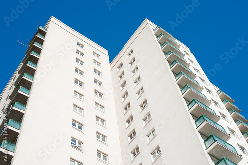 Low angle view of a high rise residential apartment block against a clear blue sky.