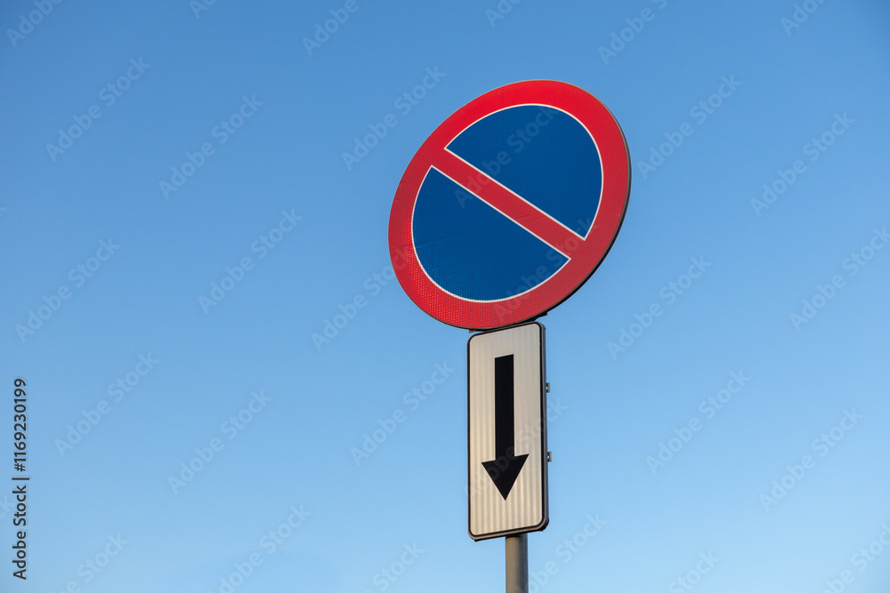 No parking traffic sign with downward arrow on clear blue sky background, indicating restricted parking zone below the sign No parking traffic sign with downward arrow on clear blue sky background, indicating restricted parking zone below the sign