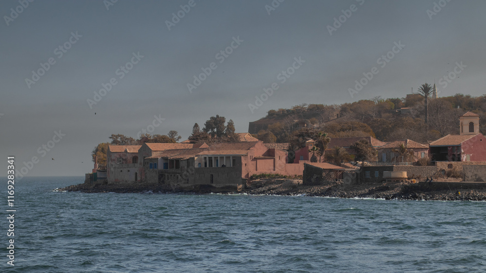View of ilee de goree, slave island in the bay of Dakar, export point for slaves from africa to the world. Evening light with sun, cottages and houses at the beach.