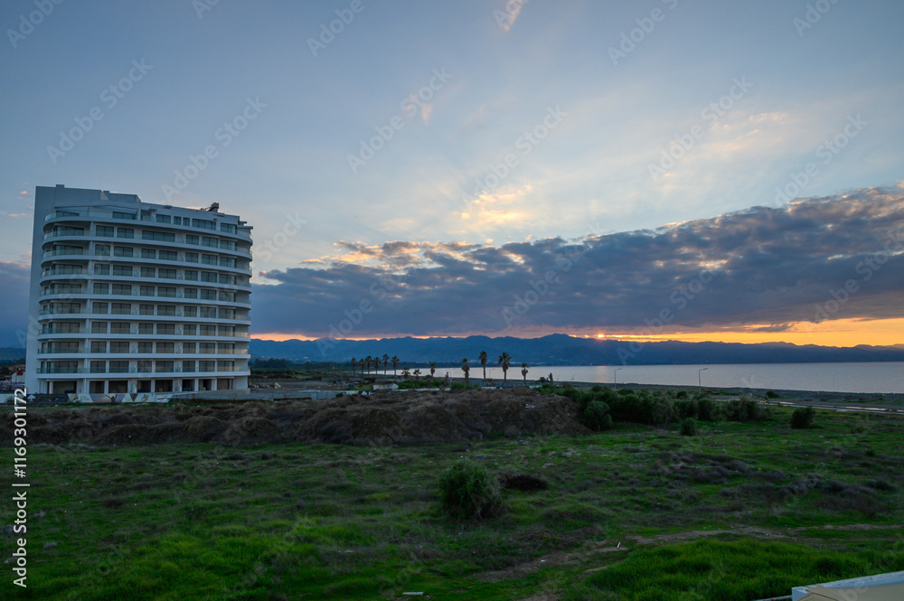 Sunset over the serene coastal landscape with a modern building in the foreground Sunset over the serene coastal landscape with a modern building in the foreground