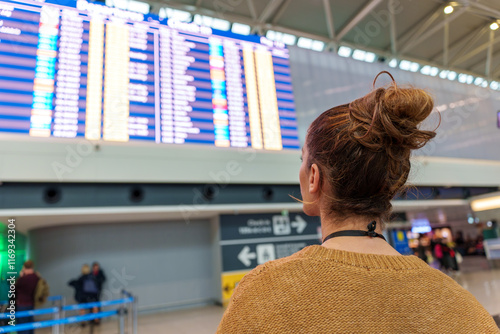 Traveler checking flight information board near boarding gate during airport wait