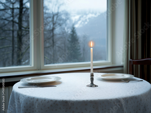 romantic candlelit table with two plates, set by window overlooking serene snowy landscape photo