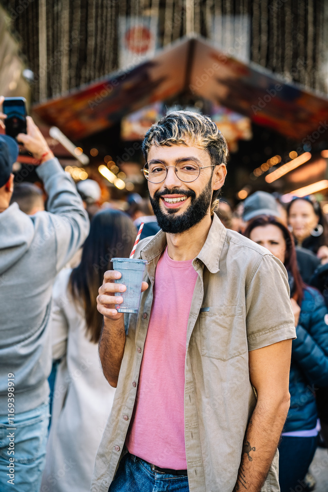 Young man smiling and holding a smoothie at a street food market Young man smiling and holding a smoothie at a street food market