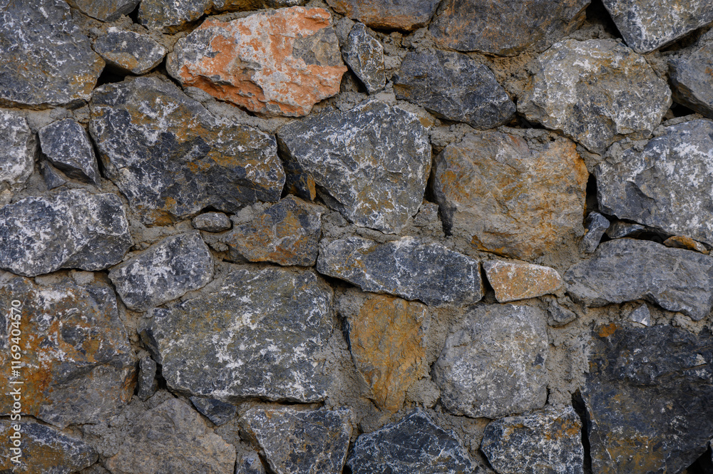 Rustic stone wall showcasing textured surfaces and varied hues in an outdoor setting Rustic stone wall showcasing textured surfaces and varied hues in an outdoor setting