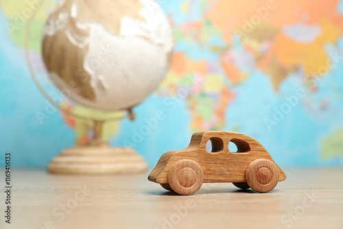 Wooden toy car and globe on table against world map, selective focus. Road trip photo