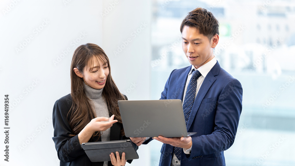 パソコンを使って話す男女2人のビジネスマン