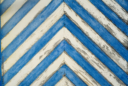 Puerta vieja de tablones de madera en diagonal pintados a rayas blancas y azules photo