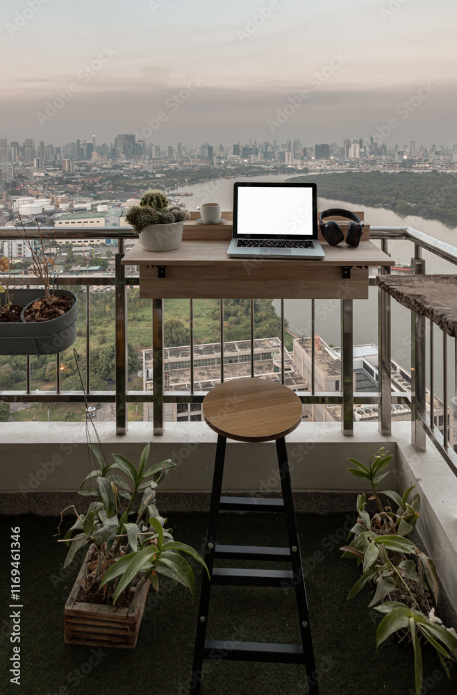 Relaxation area on Condominium balcony overlooking city view. Working space with Laptop, Ear headphones, Tea cup and Cactus pot on Folding deck rail table hanging railings, Decorated balcony.