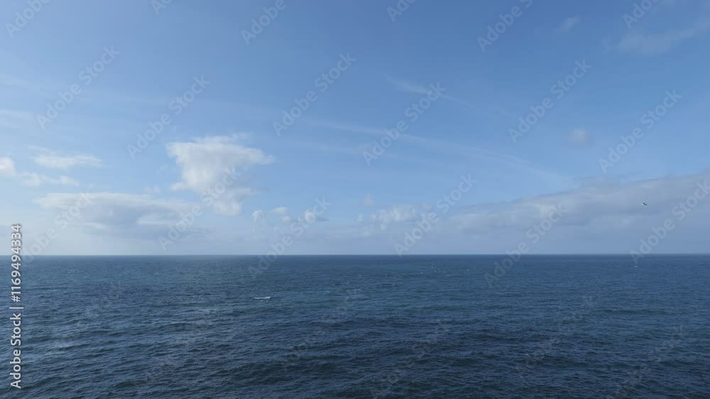 Open ocean under a clear blue sky with clouds. Open ocean under a clear blue sky with clouds.