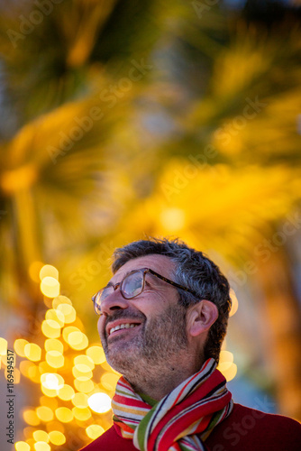 Photos Man in colorful scarf admiring festive palm tree lights at night