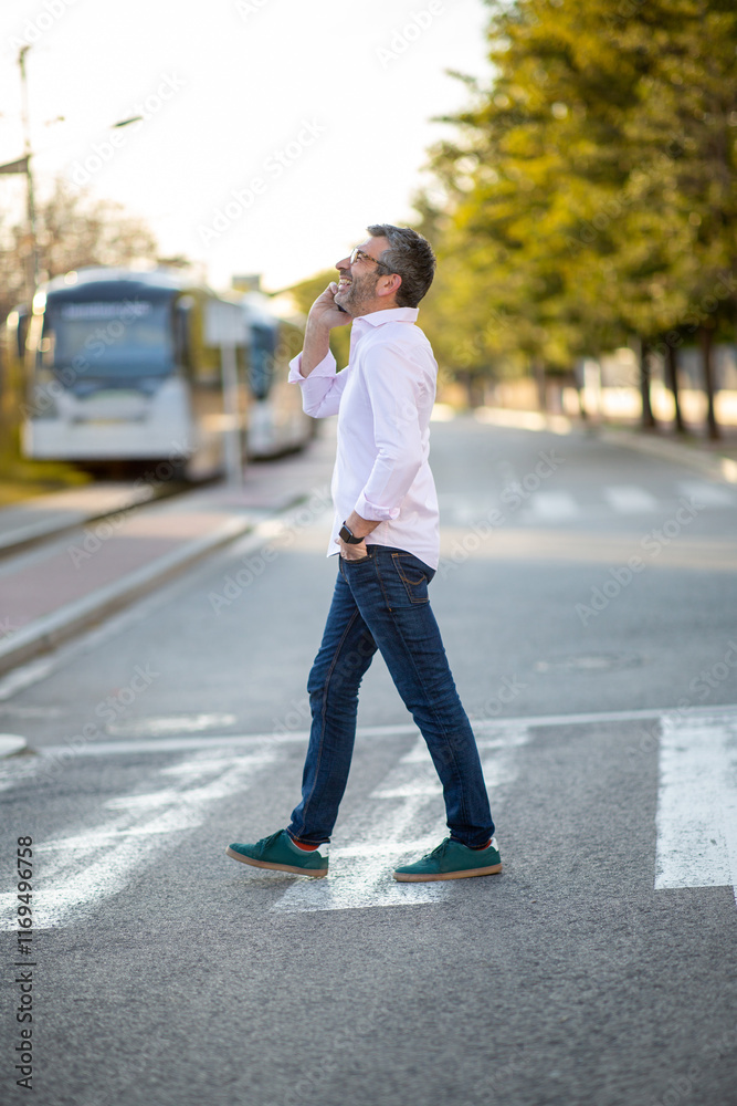 Man crossing street while talking on smartphone Man crossing street while talking on smartphone