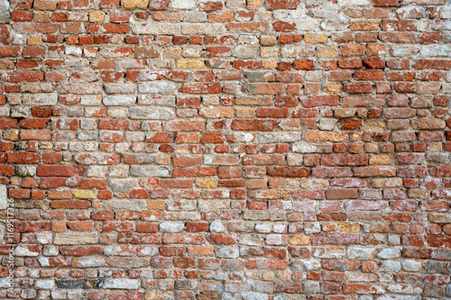 Obraz na płótnie Brick wall with pieces of plaster. Wall of an old building in need of renovation. Aged wall texture of brick building close up. Grunge background with red and white blocks and layers of cement stucco w salonie