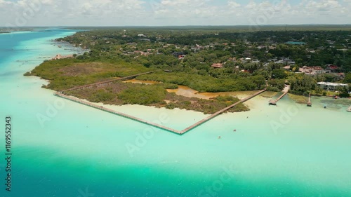 Toma aérea de dron del Parque Ecológico de Bacalar, su laguna color turquesa, su muelle de madera y sus manglares.