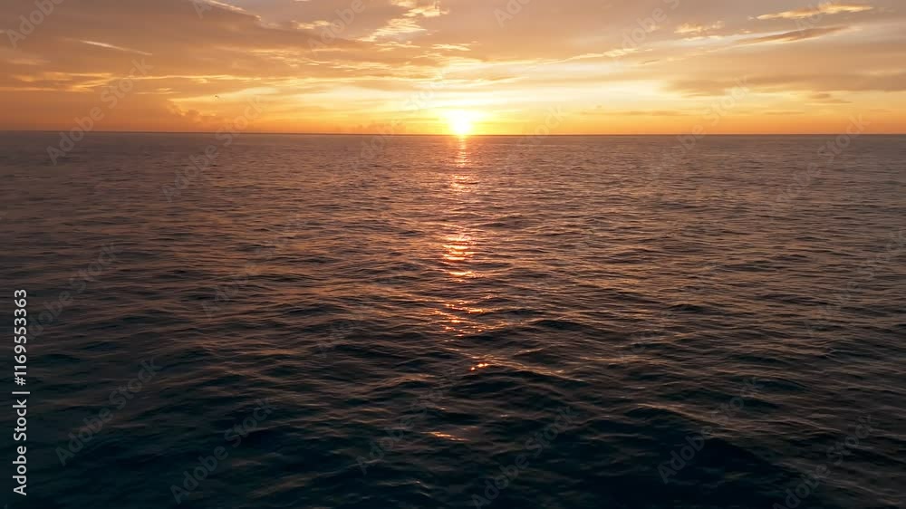 Toma aérea de dron volando sobre un calmado mar, descubriendo de un épico, hermoso y dorado amanecer en las playas de Cancún