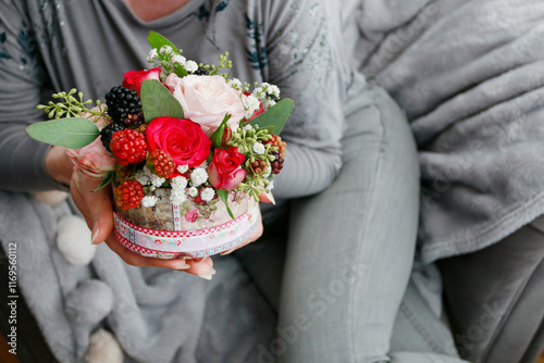 Woman holding a miniature flower box with roses and other plants.