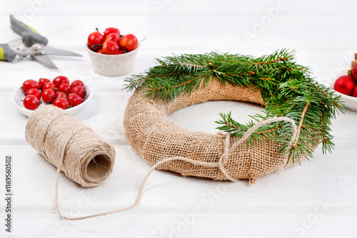 Obraz na płótnie Florist at work: woman shows how to make classic Christmas door wreath with fir twigs, red balls, small apples and cones. Step by step, tutorial. w salonie