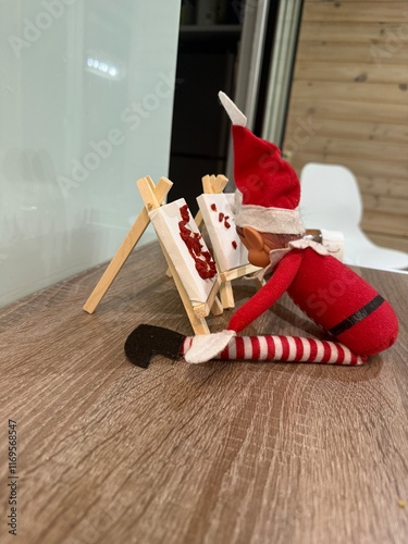 lutin farceur de noel peignant un tableau avec du ketchup
