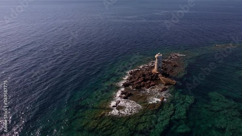 Drone soars over Faro Mangiabarche: calm waters, rugged rocks, and blue skies paint a serene Sardinian view. photo