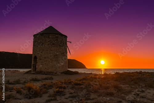 Kolorowy zachód słońca  z widokiem na stary wiatrak nad morzem na piaszczystej plaży, grecka wyspa Lefkada, krajobraz photo