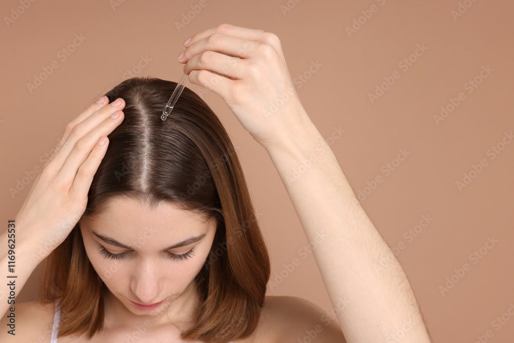 Hair loss problem. Girl applying serum onto hairline on beige background, closeup Hair loss problem. Girl applying serum onto hairline on beige background, closeup